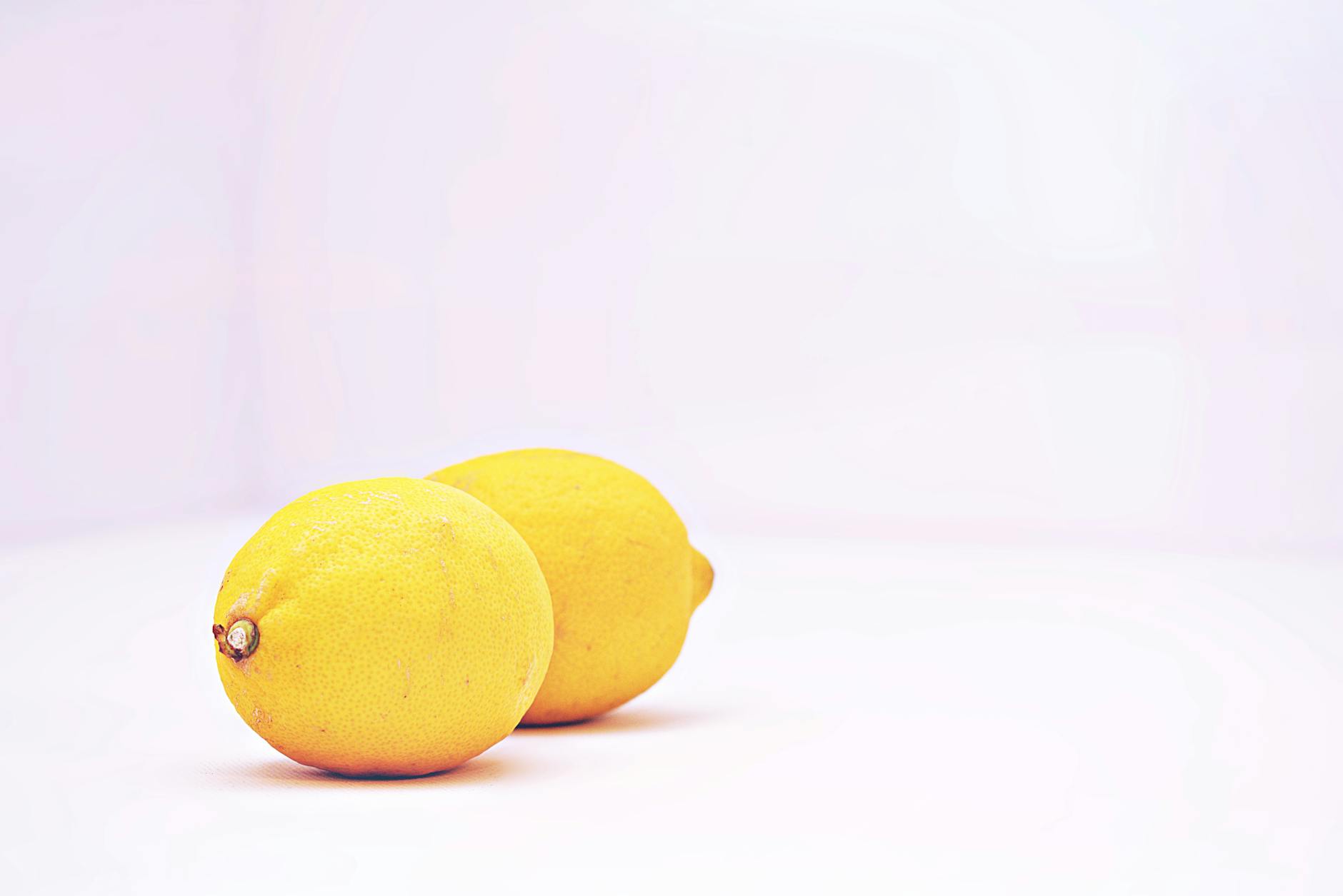 Two vibrant lemons on a minimalistic white background, representing freshness and sensory reset