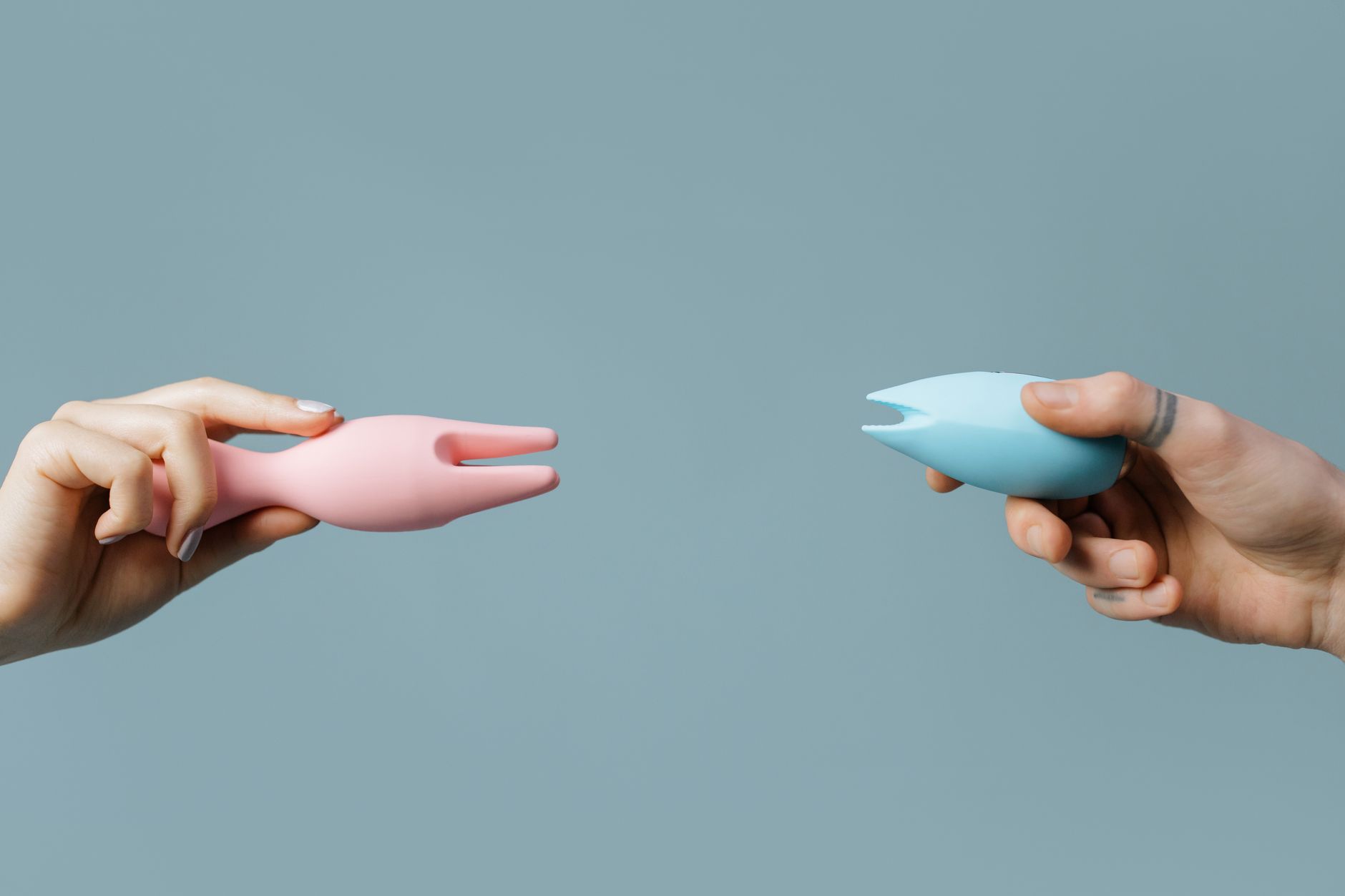 A hand holding an orange vibrator against a minimalistic purple backdrop, showcasing modern sensuality and control.