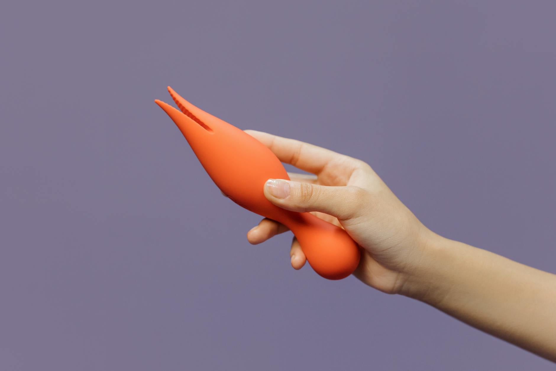 Hand holding a yellow lemon vibrator against a purple backdrop, symbolizing warmth and accessible pleasure
