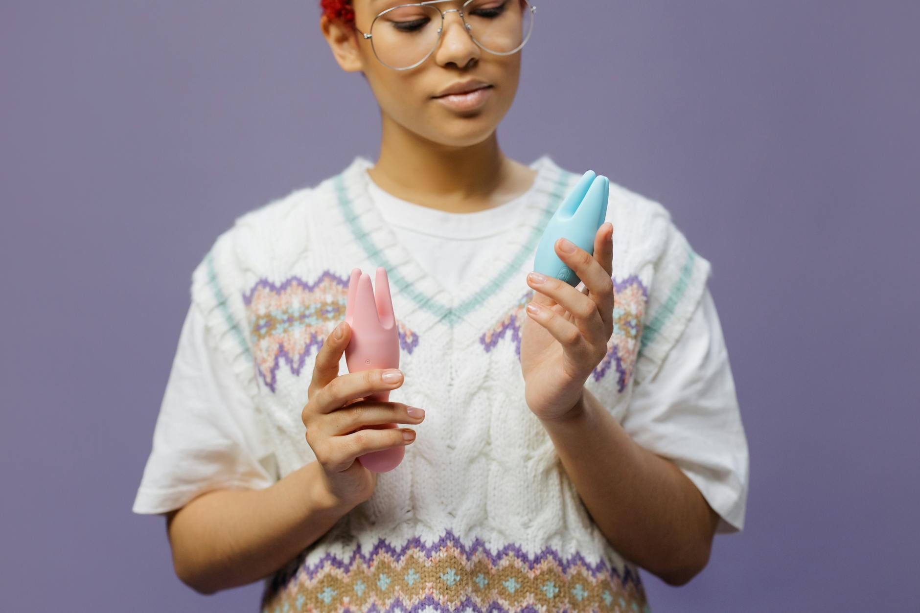 Hand reaching over a collection of colorful vibrators on a table, symbolizing choice and partnership