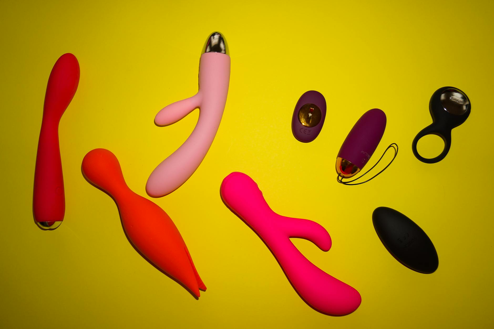 A vibrant display of various clitoral vibrators on a bright yellow background